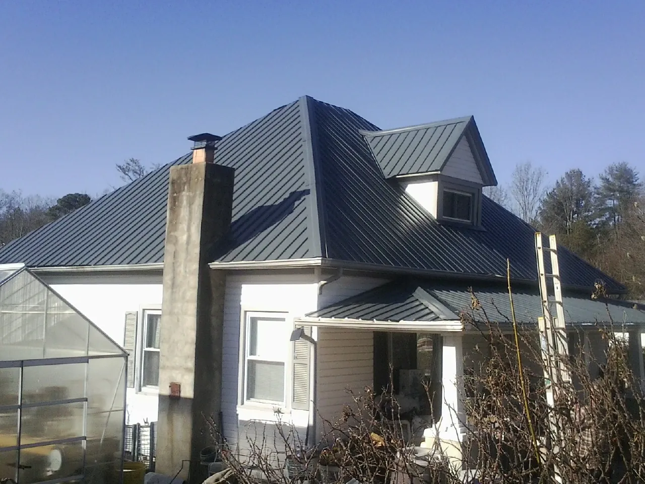 Dark blue standing seam metal roof on a white farmhouse with dormer — Slate & Tile Roof Repair by Roofing Brothers in Boiceville