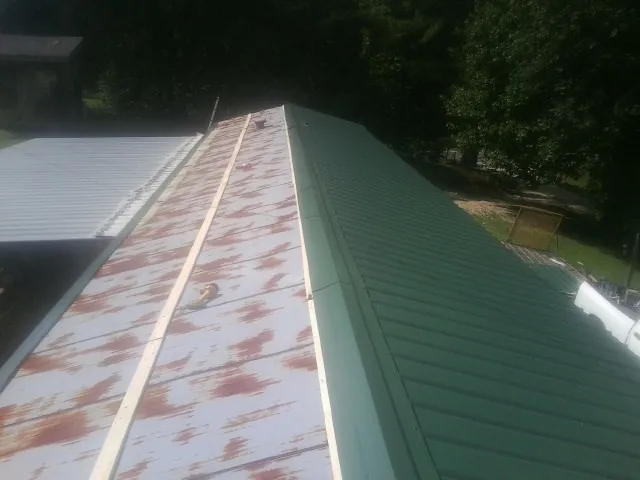 Old rusted panels beside newly installed green metal roofing — Wind Damage Roof Repair by Roofing Brothers in Boiceville