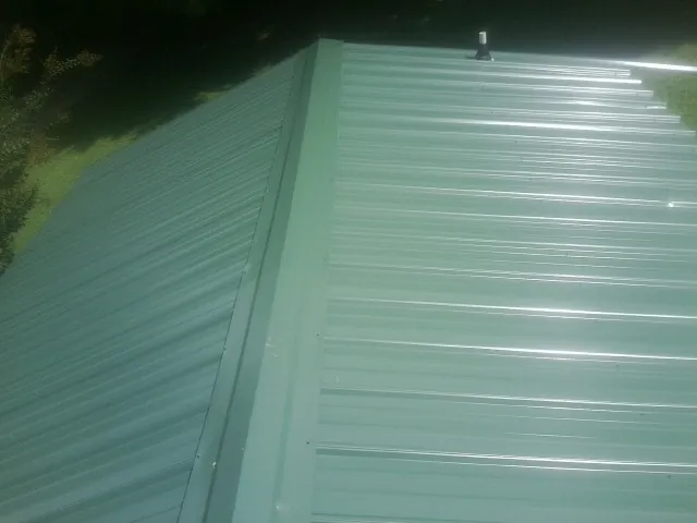 New green metal panels meeting at the ridge of a roof — Flat Roof Repair work by our crew in Boiceville