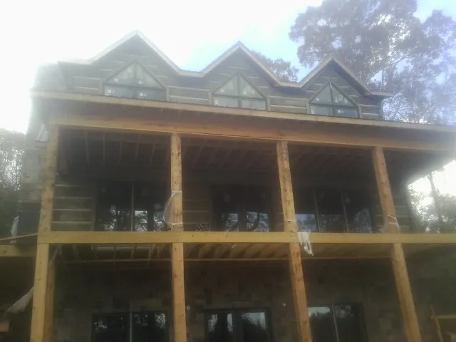 Dormers and porch framing on a large log home under construction — Roof Coating work by our crew in Boiceville