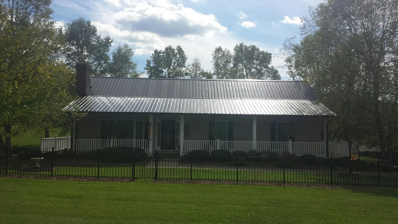 Gray metal roof on a brick ranch with a full width front porch — Gutter Guard Installation work by our crew in Boiceville