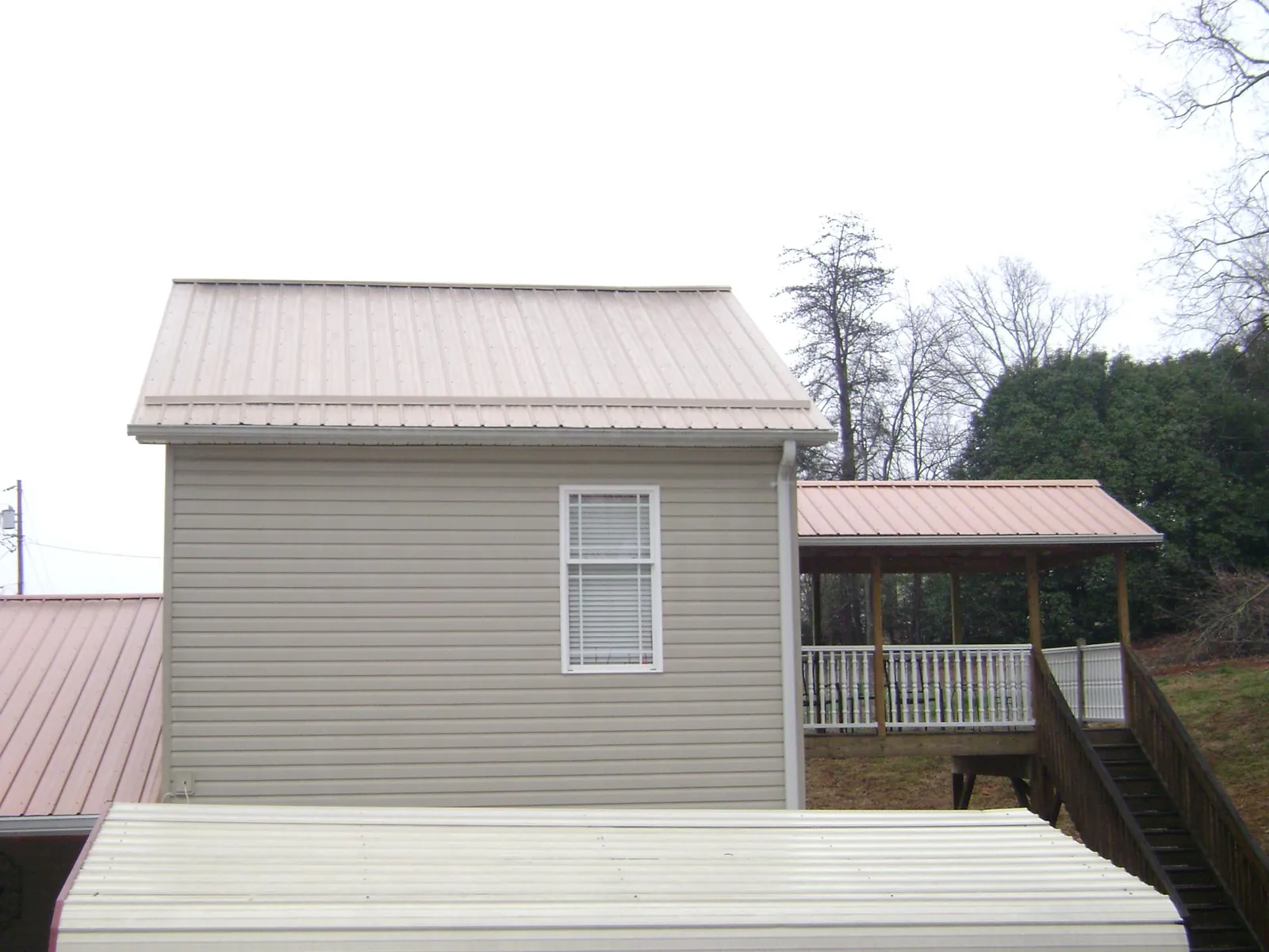Tan metal roofs on a two story addition and attached porch, from a Roof Replacement job in Boiceville
