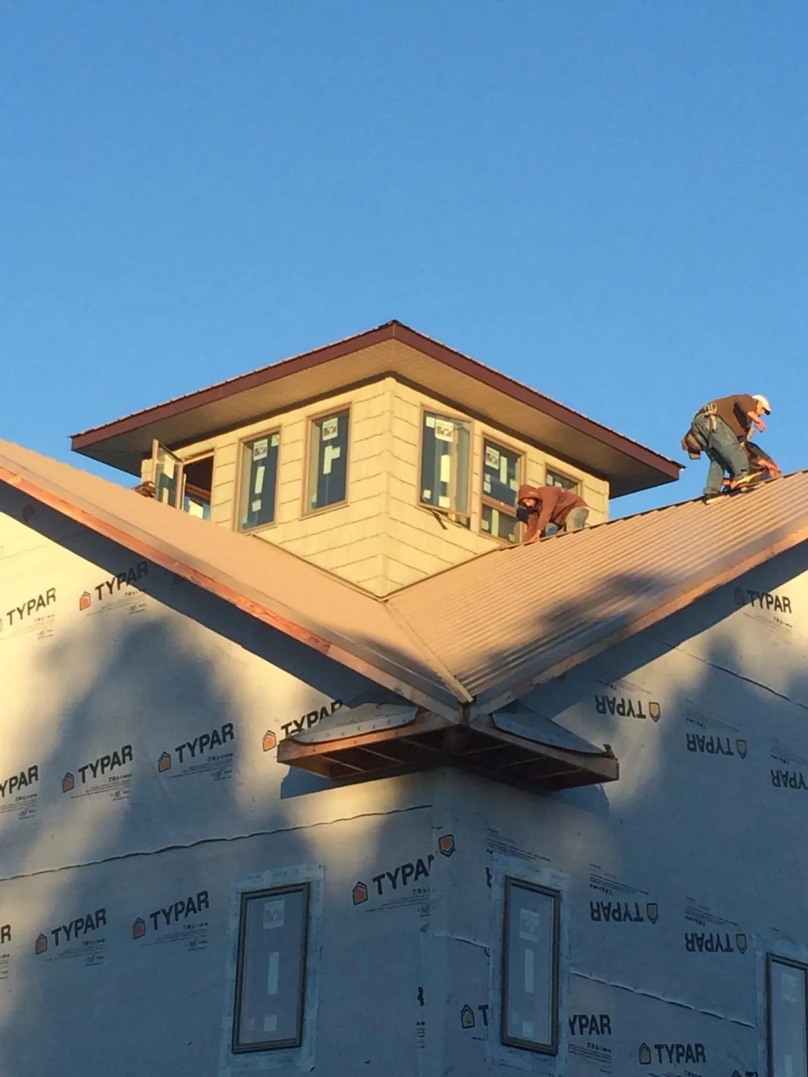Roofers working around a rooftop cupola on a new metal roof at sunset — Roof Waterproofing in Boiceville by Roofing Brothers
